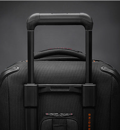 Black suitcase with handle and visible brand logo on a dark background