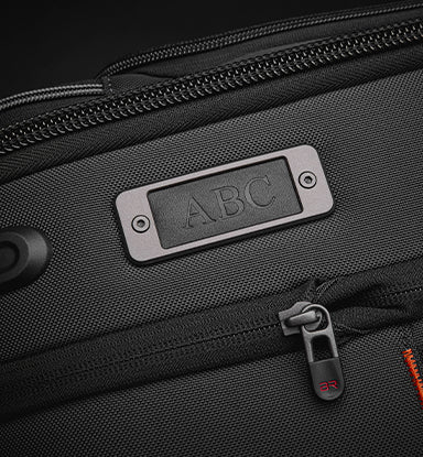 Black suitcase with a personalized nameplate on a dark background