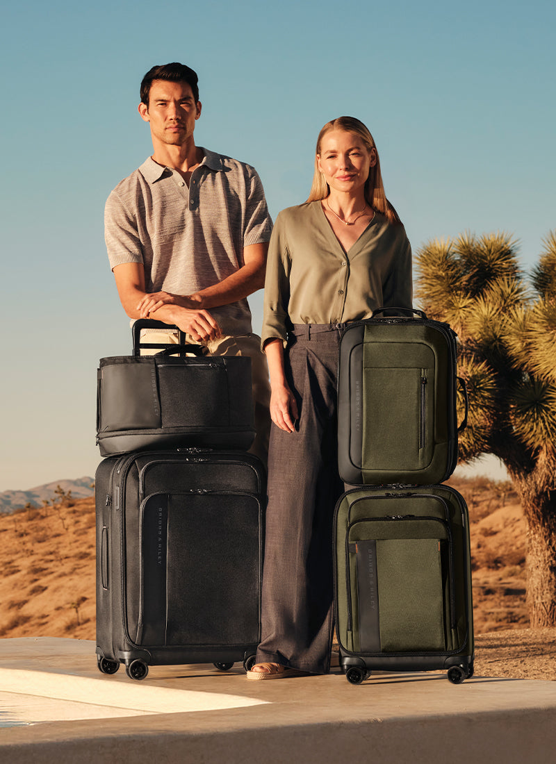Two people standing with suitcases in a desert setting