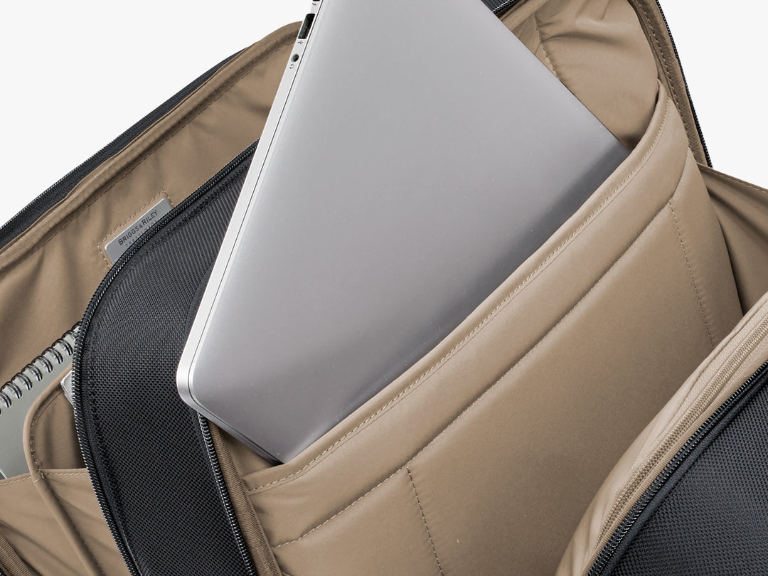 An interior view of the laptop compartment in the Briggs & Riley At Work Large Cargo Backpack shows a 17-inch laptop and an iPad safely stowed away.