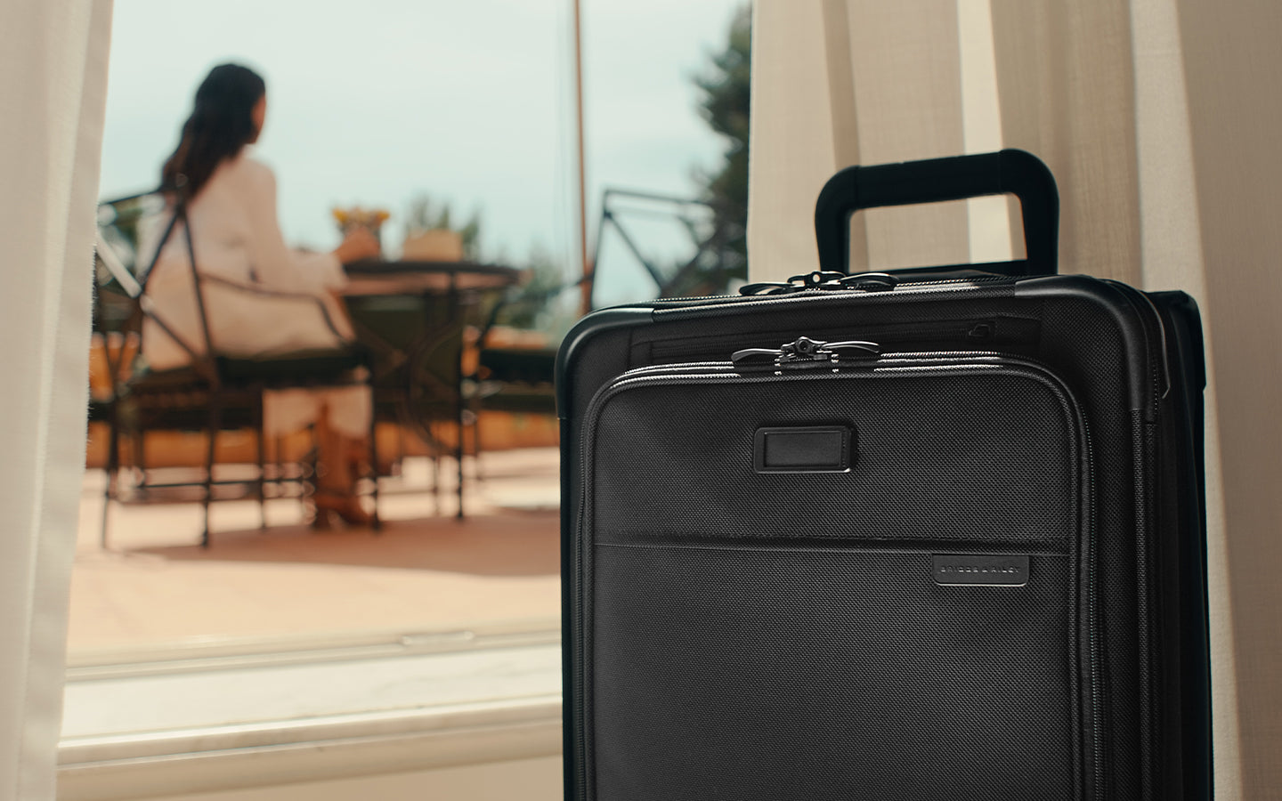 Carry-on baseline spinner with woman in background