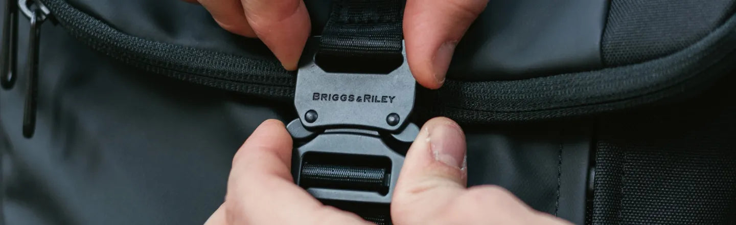Close-up of a Briggs & Riley backpack buckle being fastened.